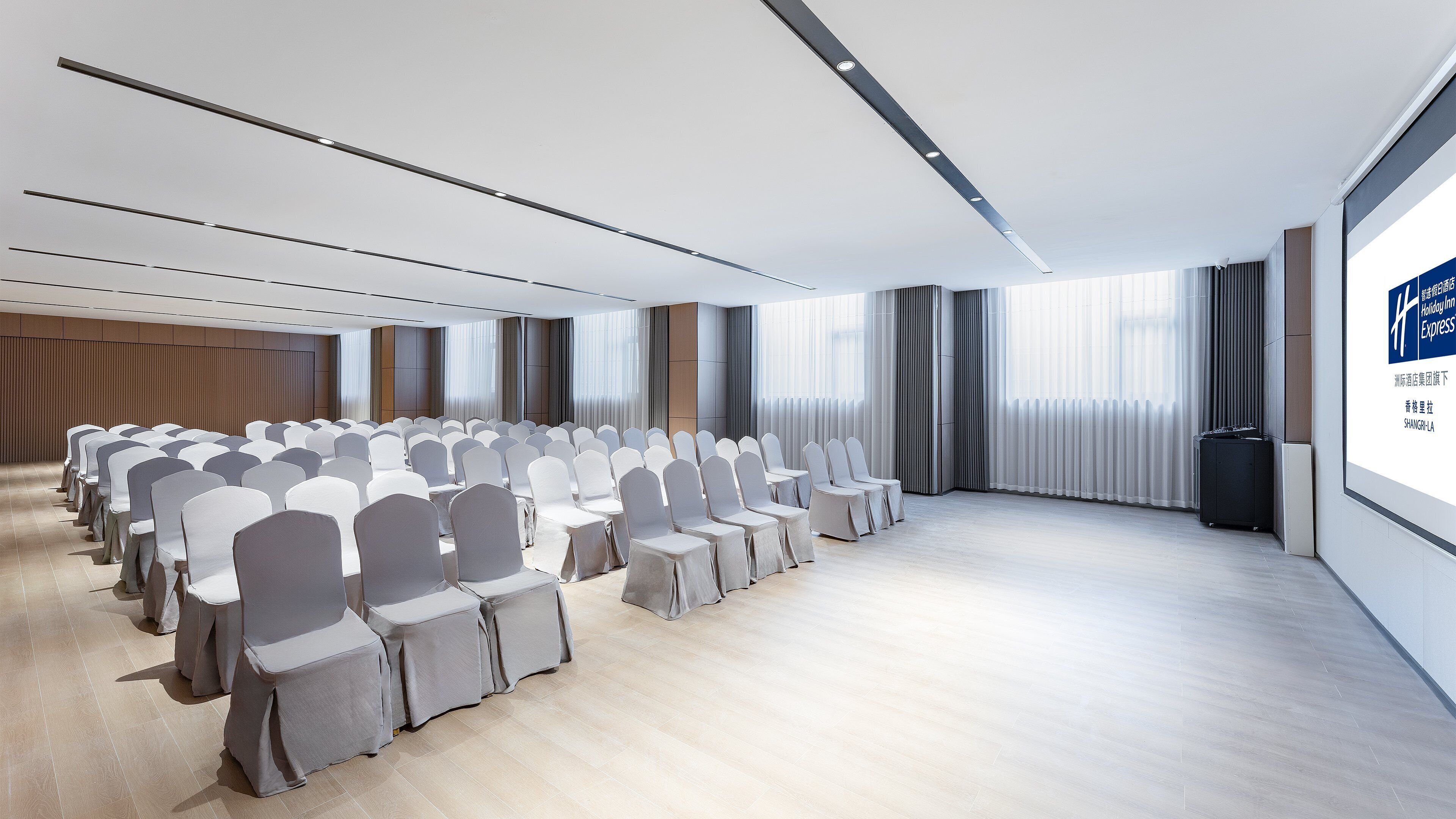 A conference room with rows of chairs, a large screen, and a modern interior design.