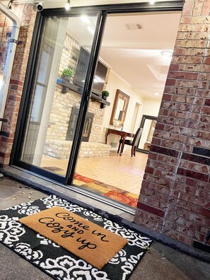 A modern entrance with a glass door, a brick wall, and a welcome mat.