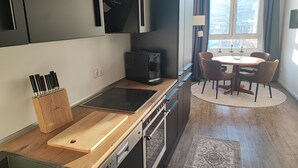 Een moderne keuken met een inbouwoven, een koffieapparaat en een houten snijplank.