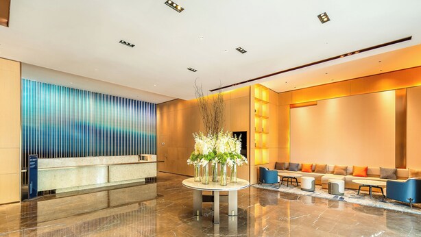 A modern lobby with a reception desk, seating area, and a decorative centerpiece.