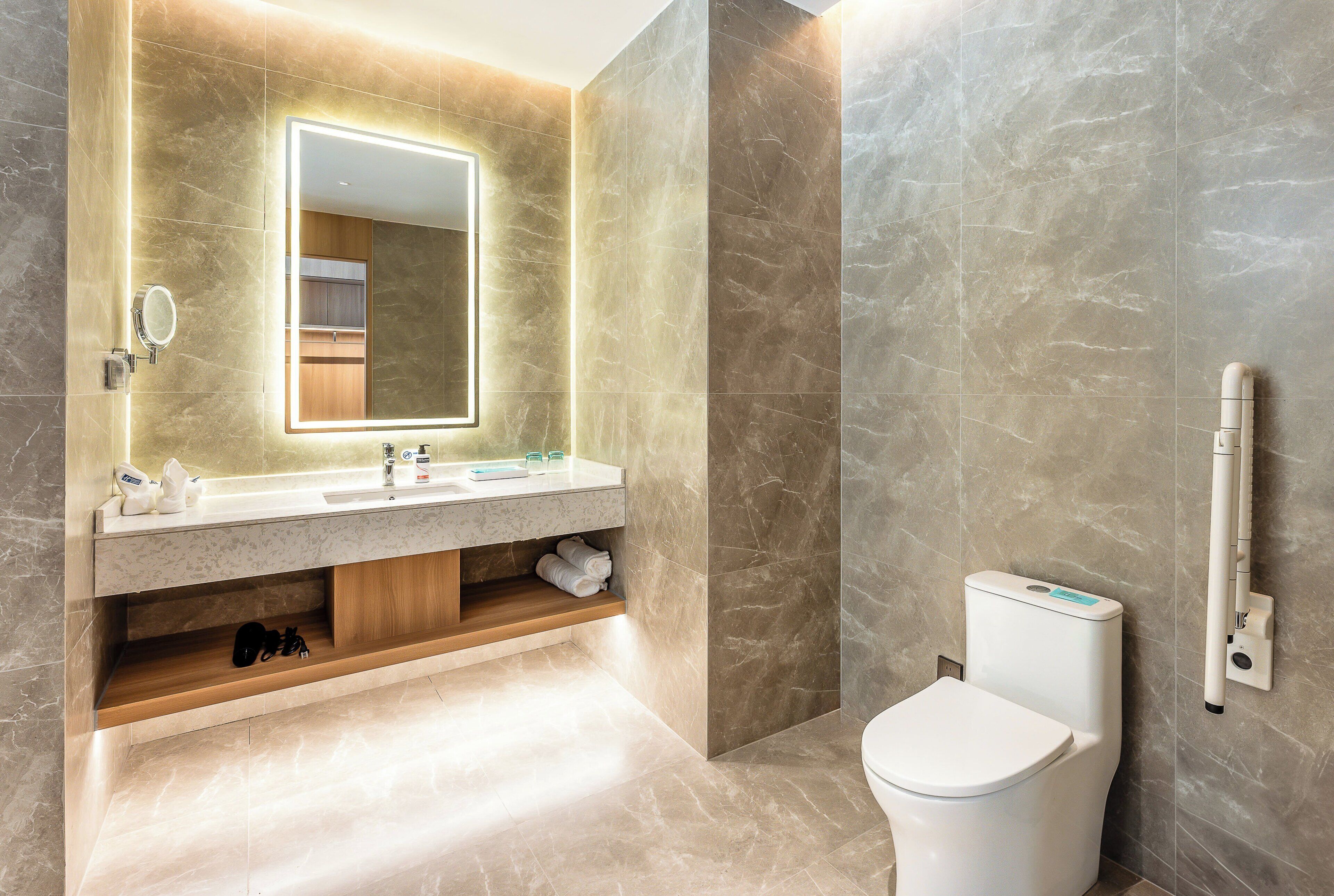 Ein modernes Badezimmer mit Waschtisch aus Marmor, einem großen Spiegel und einer Toilette mit Bidetfunktion.