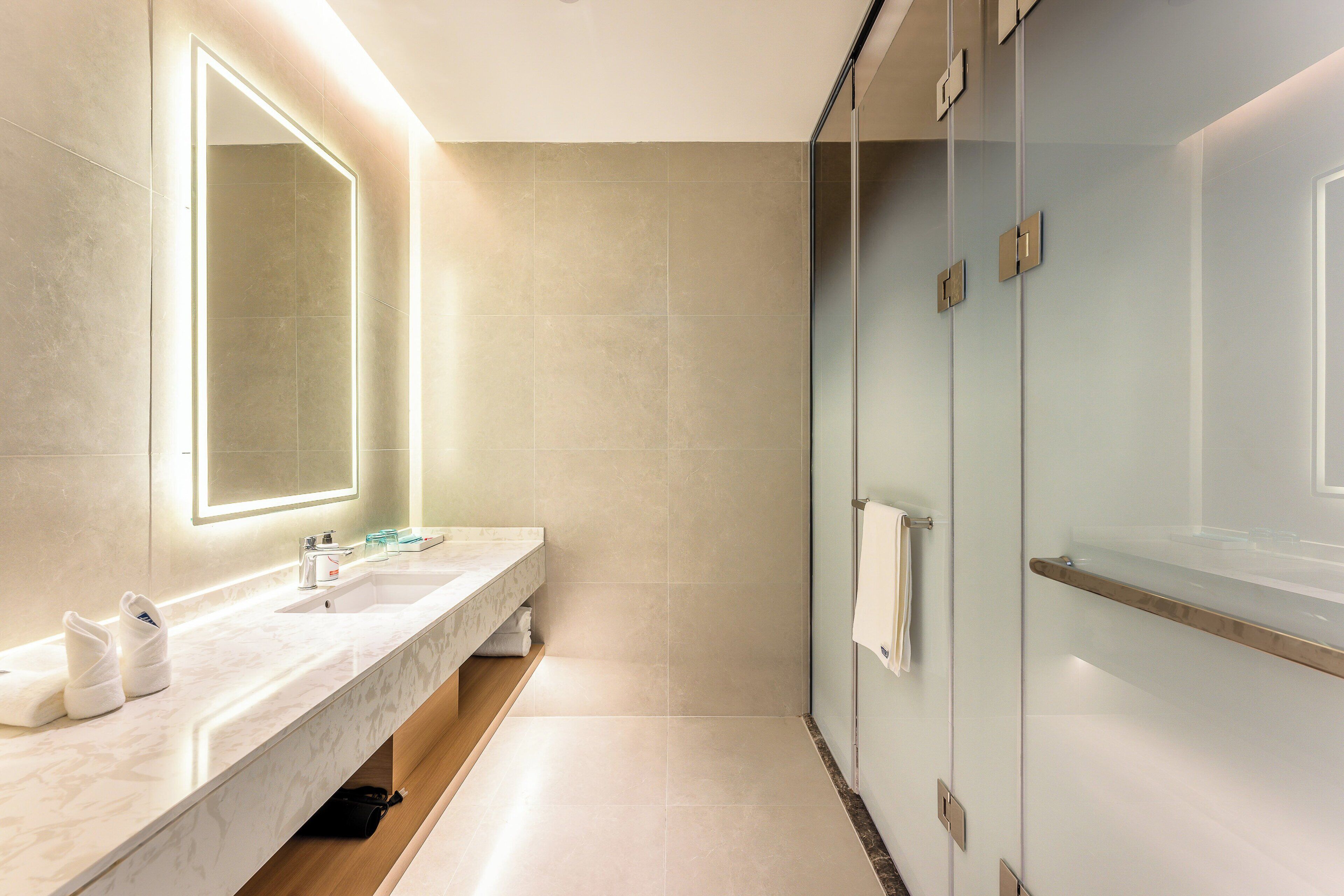 Un baño moderno con tocador de mármol, un espejo grande y cabina de ducha de vidrio.