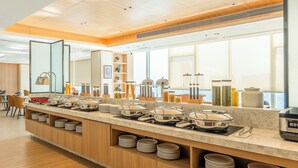 A modern kitchen with a long counter, various cooking appliances, and a large window providing natural light.