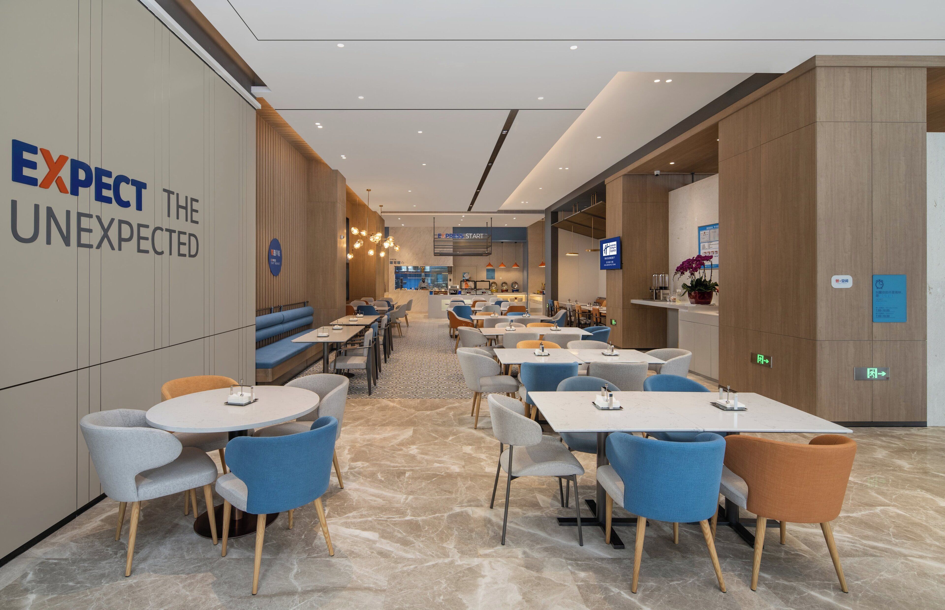 En modern hotellobby med sittgrupper, bord och en receptionsdisk.