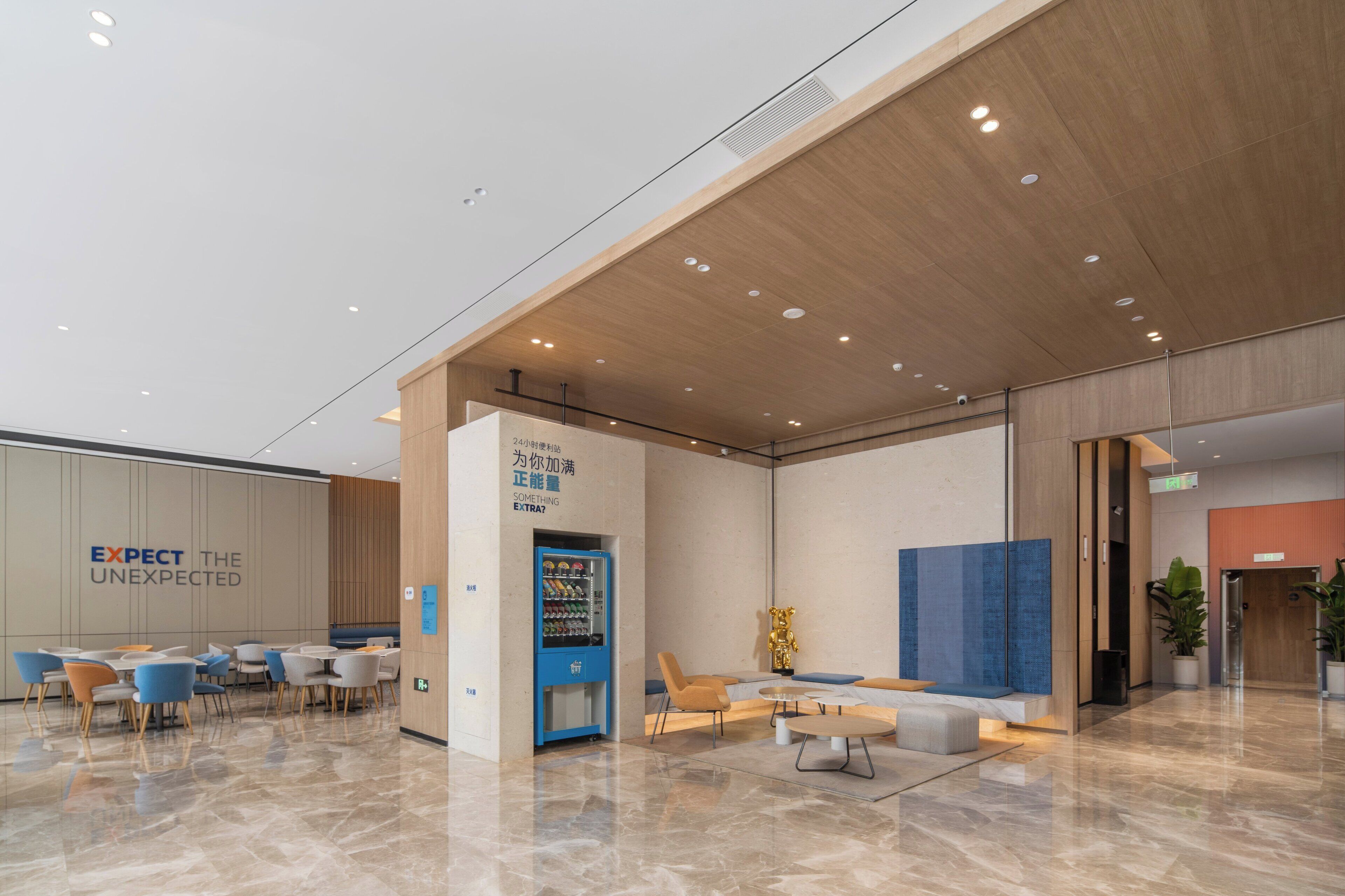 A modern lobby with seating areas, a vending machine, and a wall with motivational text.