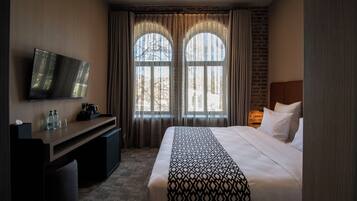 Ein Hotelzimmer mit Bett, Schreibtisch, Fernseher und großen Fenstern.