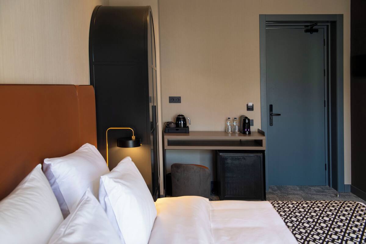 Una habitación de hotel con una cama, un escritorio, una cafetera y una puerta.