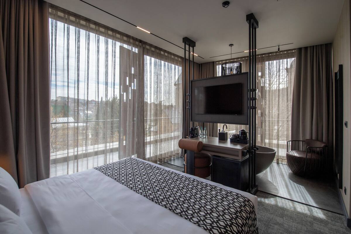 Habitación de hotel con una cama grande, televisión, lavamanos y una silla.
