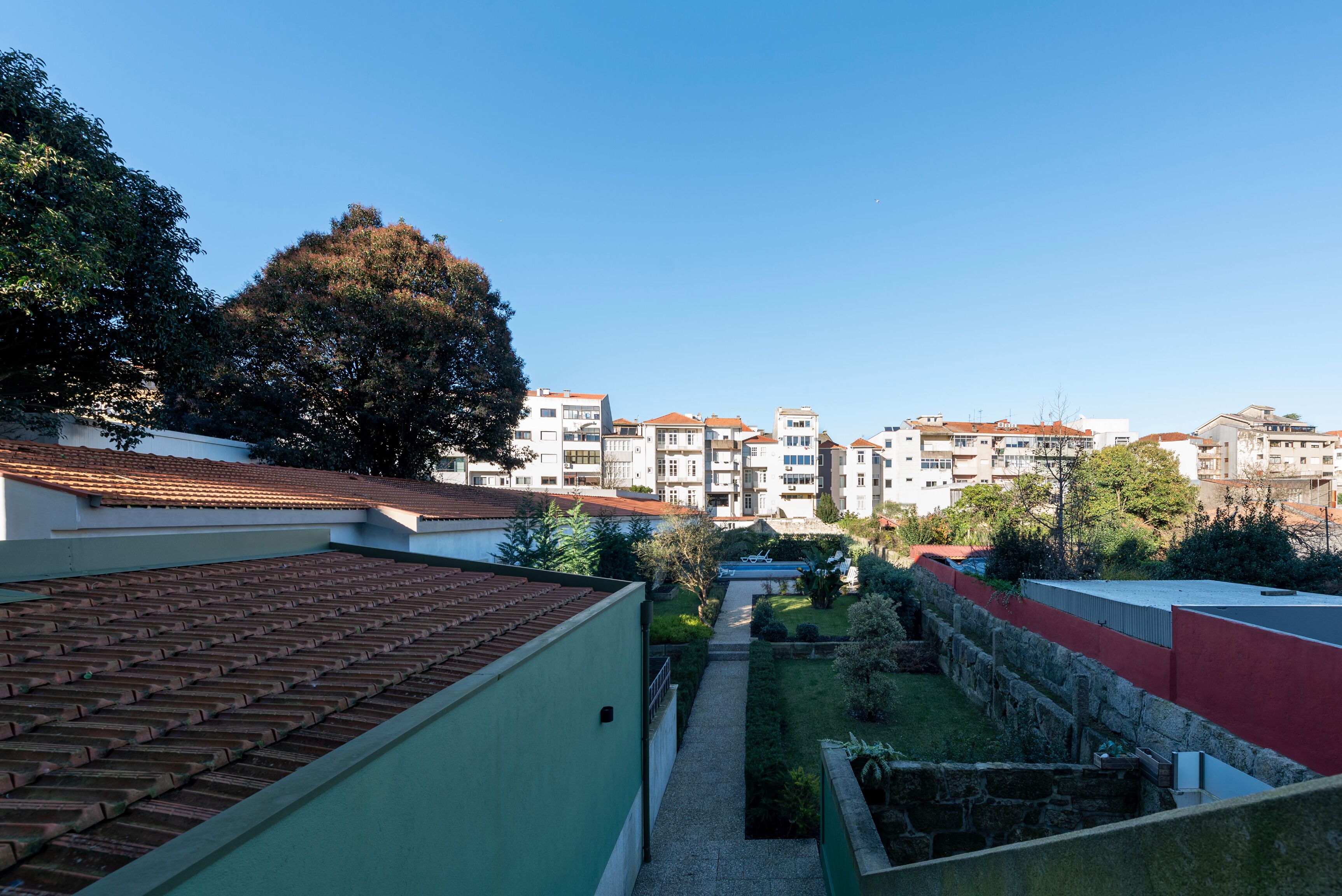 Un pati amb teulada d'estuc, parets de pedra i un camí que condueix a un edifici amb diverses finestres i balcons.