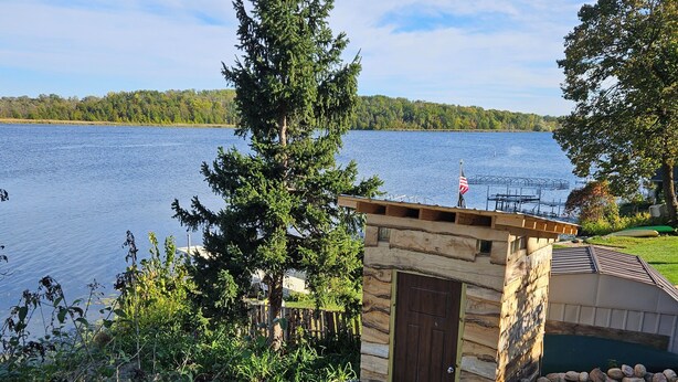 A cabin with a wooden exterior, a small porch, and a view of a lake.