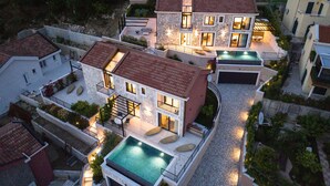 Una casa moderna de varios pisos con piscina, fachada de piedra y varios balcones.