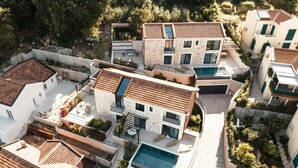 Un moderno complejo residencial con varias casas, una piscina comunitaria y un camino de piedra.