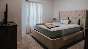 A bedroom with a bed, a bedside table, a lamp, and a television on a stand. - Beautiful Townhouse Near the Parks, pool, gym,wifi and more! (Kissimmee)