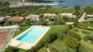 A residential area with a swimming pool, houses, and a marina in the background. - Villa 'Alba Baja Sardinia' with Sea View, Shared Pool, and Wi-Fi (Baja Sardinia Arzachena)