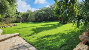 A well-maintained grassy area with a stone pathway leading to a stone wall. - Villa 'Alba Baja Sardinia' with Sea View, Shared Pool, and Wi-Fi (Baja Sardinia Arzachena)