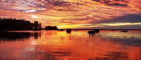 Un lago tranquilo al atardecer con barcos y una orilla arbolada.