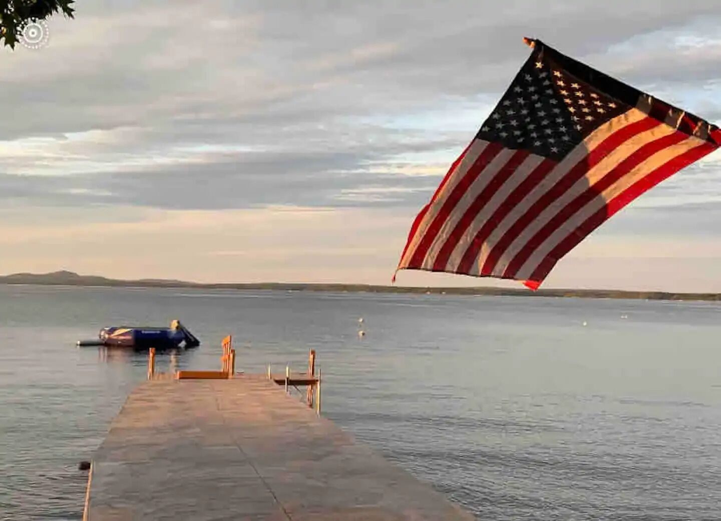 Une jetée s’avançant dans une étendue d’eau calme, avec un drapeau américain flottant au vent.