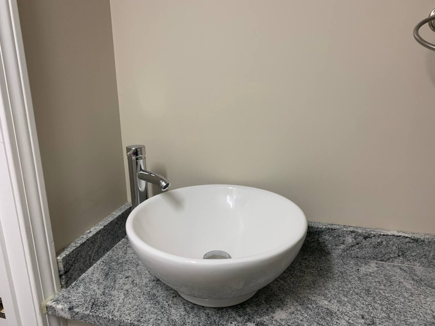 A white ceramic sink with a single faucet on a granite countertop in a bathroom.