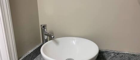 Un lavabo de cerámica blanca con un solo grifo sobre una encimera de granito en un baño.