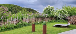 A garden with a wooden fence, a stone wall, and a wooden bench.