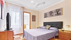 A bedroom with a bed, a television on a wooden dresser, a ceiling fan, and a painting on the wall. - Apartment 'La Bodegueta' with Private Terrace, Wi-Fi and Air Conditioning (Orba)