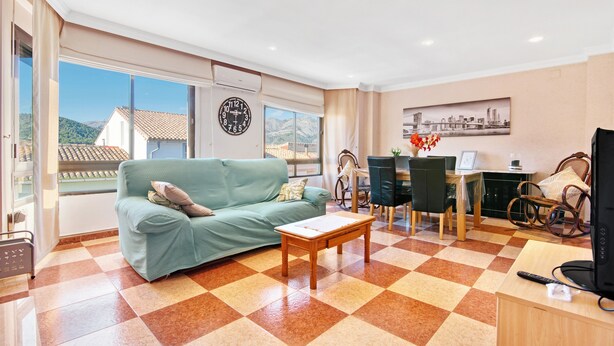 A living room with a checkered floor, a sofa, a coffee table, a dining area with chairs, and a view through large windows. - Apartment 'La Bodegueta' with Private Terrace, Wi-Fi and Air Conditioning (Orba)