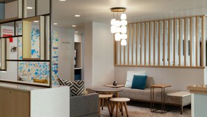 A modern living room with a sofa, coffee table, and a decorative light fixture. - TownePlace Suites by Marriott Denver North/Thornton (Thornton)
