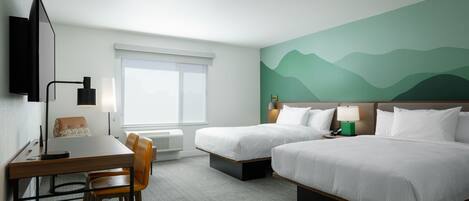 Una habitación de hotel con dos camas, un escritorio, una silla, un televisor y una ventana.