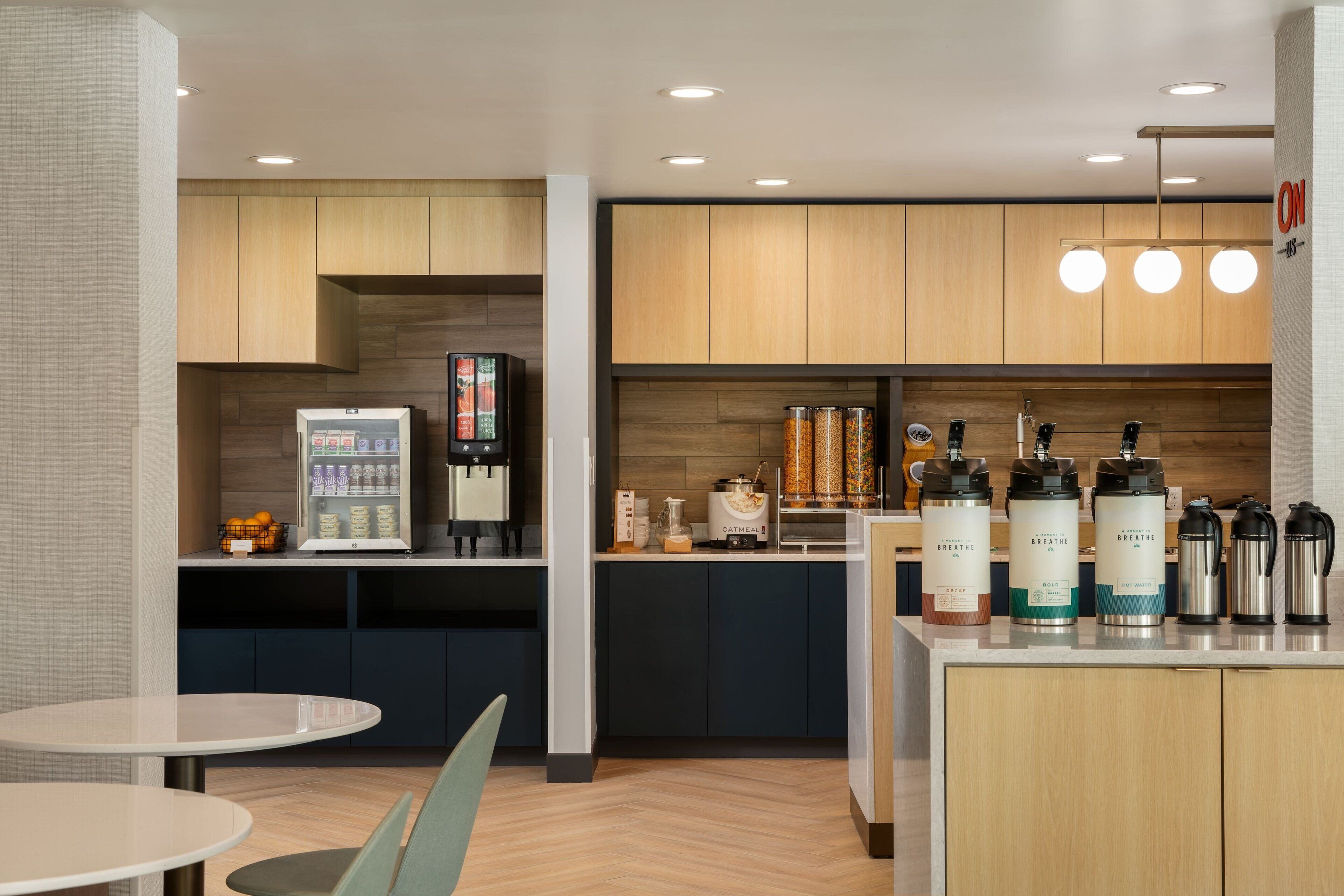A modern kitchen with wooden cabinets, a coffee machine, and various coffee dispensers.