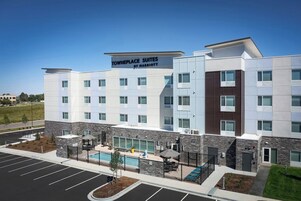 Un hotel moderno con un cartel que dice "TownePlace Suites by Marriott", que cuenta con piscina, asientos al aire libre y un estacionamiento.
