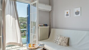 Una habitación con un sofá, una mesa con un libro y una tetera, un radiador y dos cuadros en la pared.