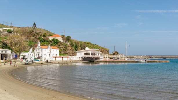 Una zona costera con playa de arena, barcos y edificios con tejados rojos.