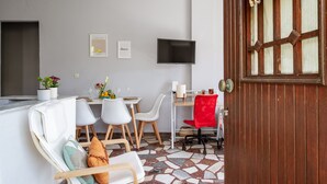 Una sala de estar moderna con comedor, televisor montado en la pared y puerta de madera con ventana.