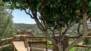 Un árbol con un banco de piedra y vistas a una colina con edificios.