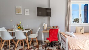 Habitación de hotel con comedor, televisor, cama y ventana con vistas.