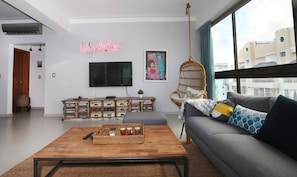 A modern living room with a wooden coffee table, grey sofa, and a TV mounted on the wall.