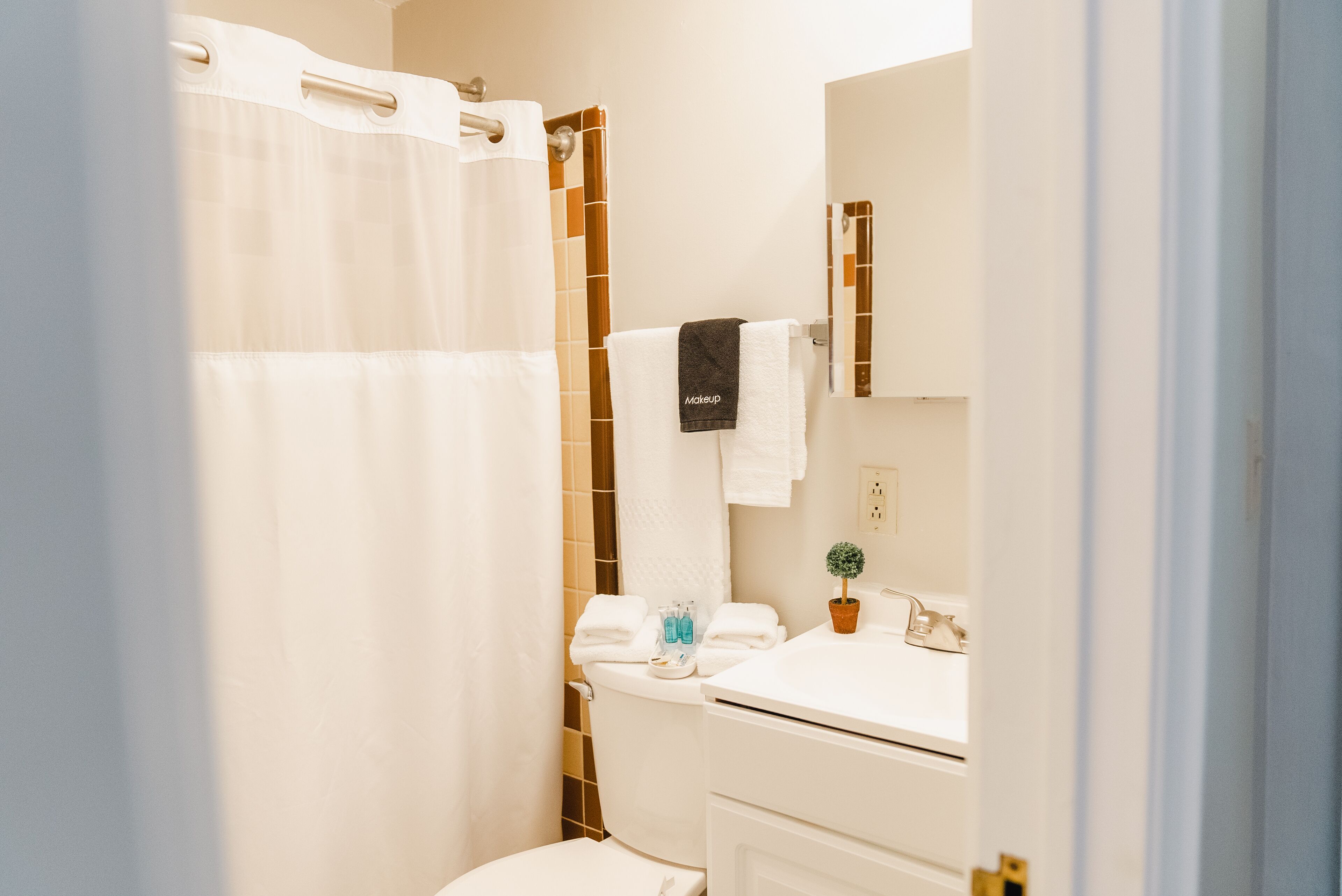 A bathroom with a shower curtain, a toilet, a sink with a mirror, and a towel rack.