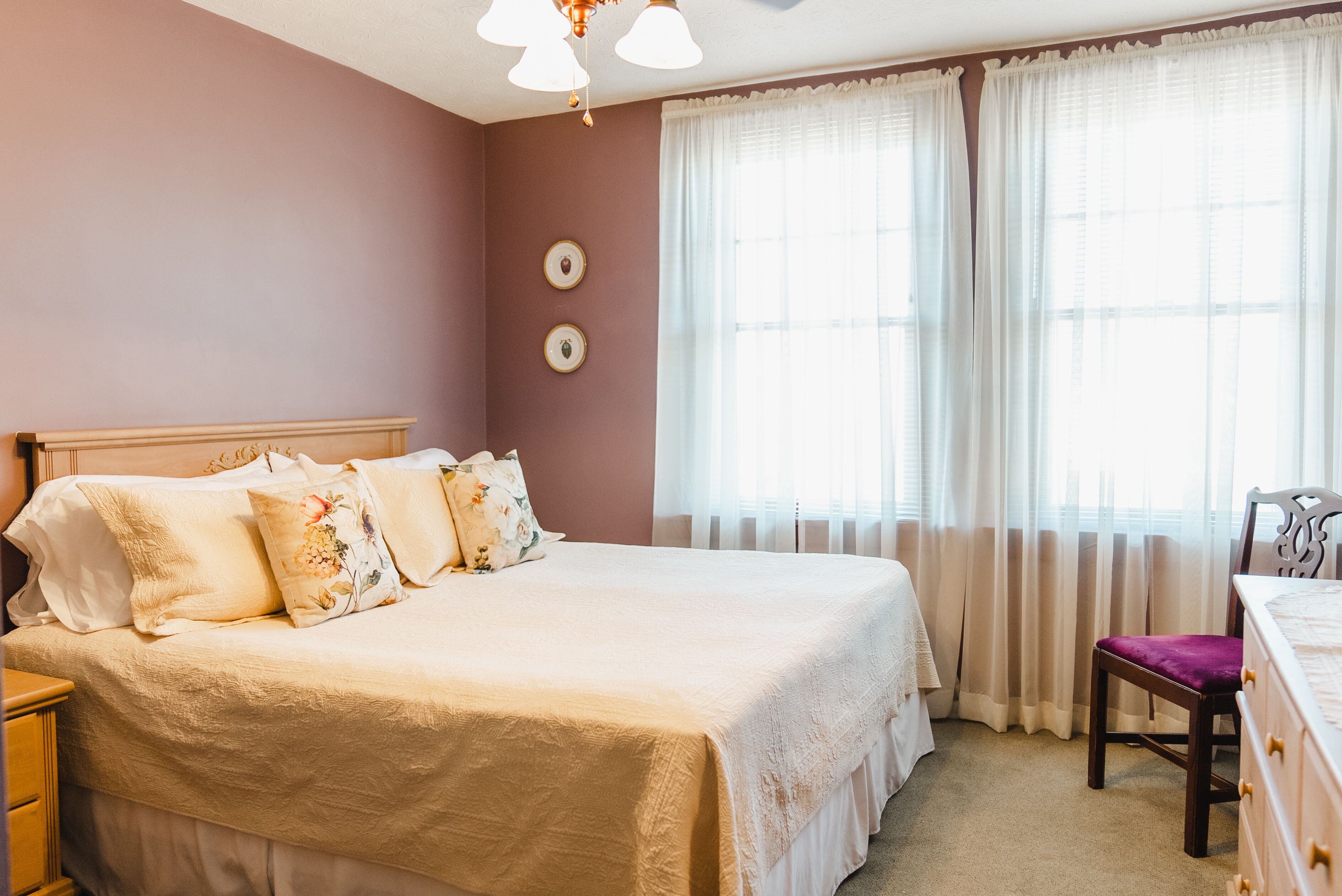 Une chambre à coucher avec un grand lit, une table de chevet en bois, une commode et une chaise.
