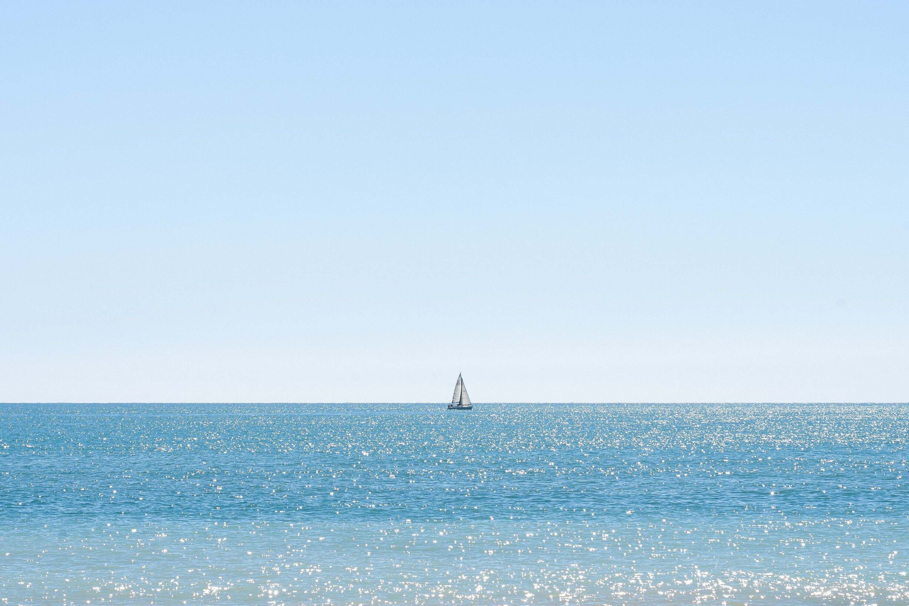 A sailboat on a calm sea with a clear sky.