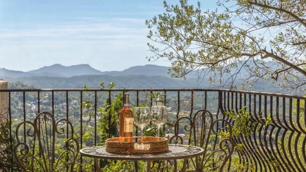 Ein Balkon mit Tisch, einer Flasche und einem Glas.