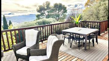 A deck with wicker furniture, a table, and chairs.