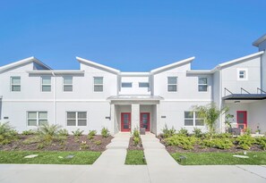 A modern multi-story building with a symmetrical facade, two red doors, and a central entrance.