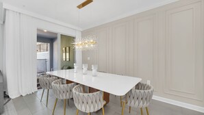 Ein moderner Essraum mit einem weißen Tisch, sechs gestatteten Stühlen und einem außergewöhnlichen Kronleuchter.