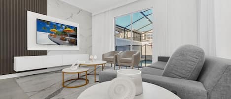 Un salon moderne avec un canapé gris, une table basse ronde et un tableau représentant une scène de plage.