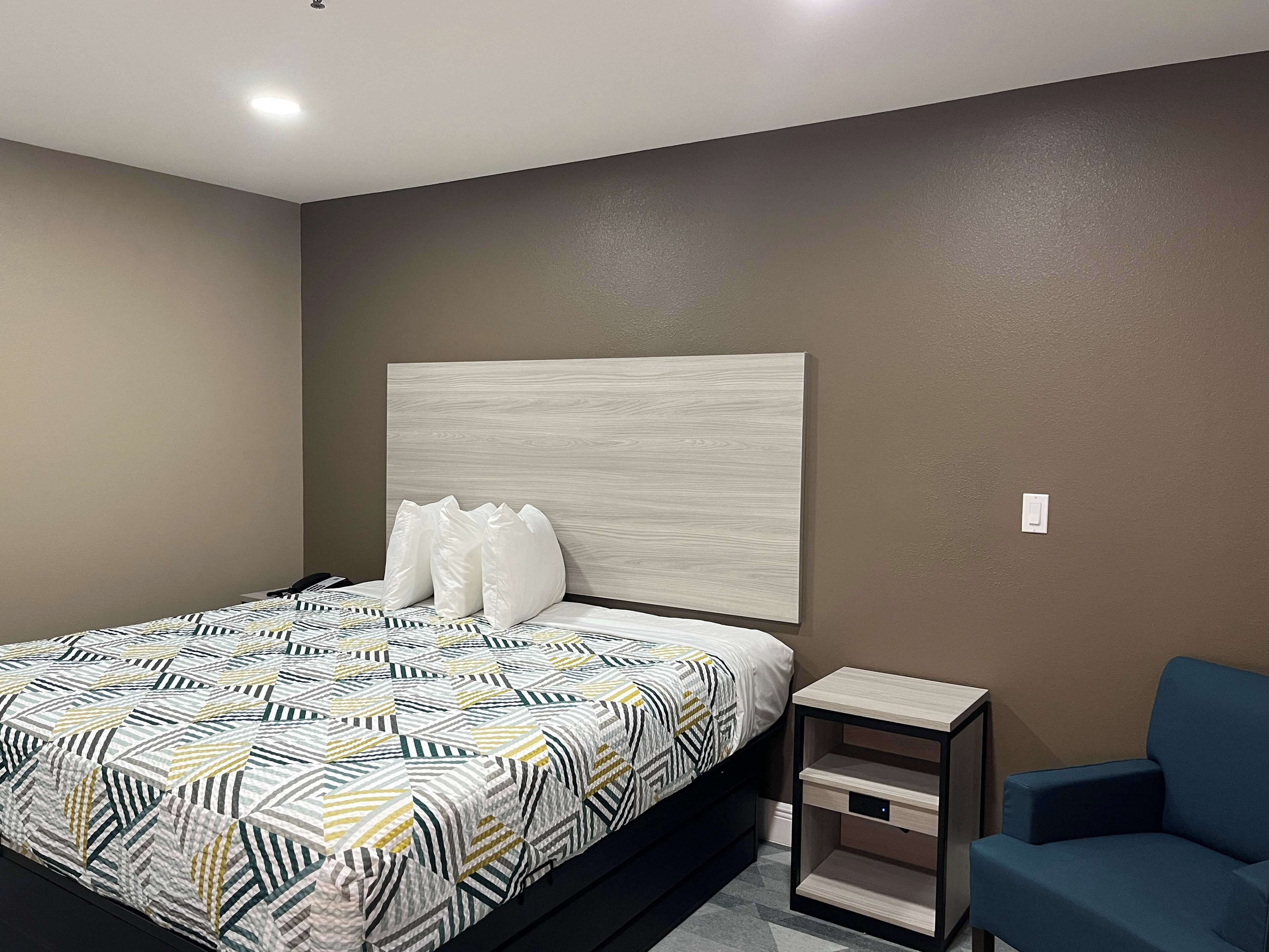 A modern bedroom with a bed, a nightstand, and a chair.