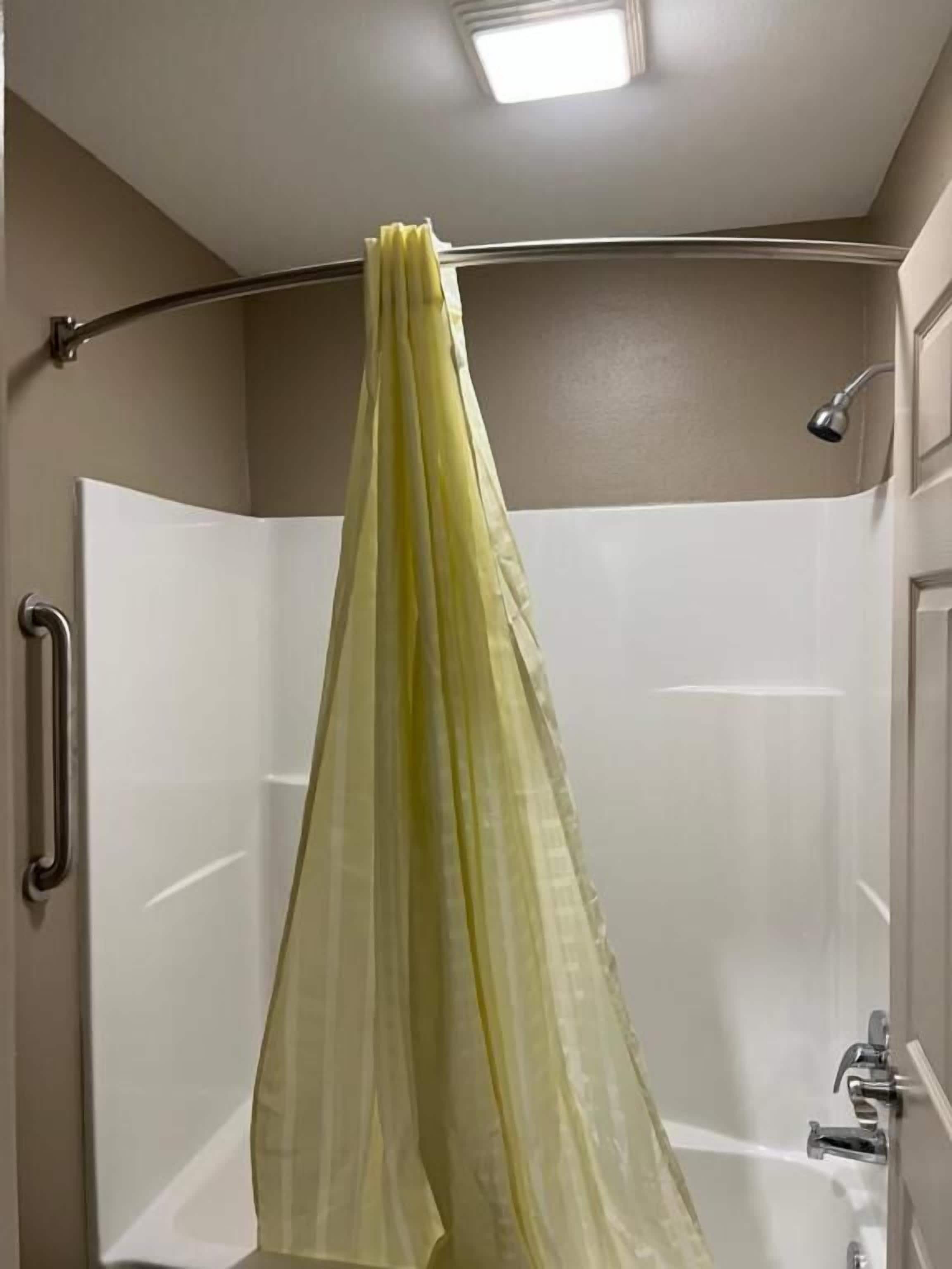 A shower area with a glass door, a handheld showerhead, and a towel rack.