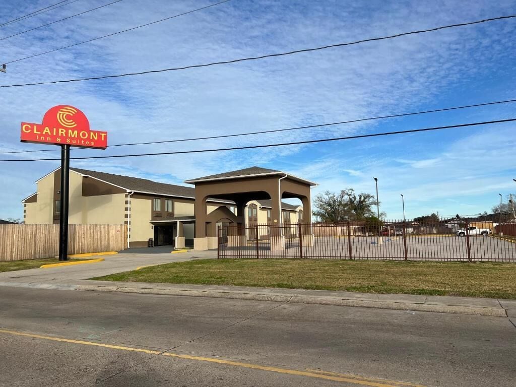 A hotel with a prominent sign, a covered parking area, and a fenced property.