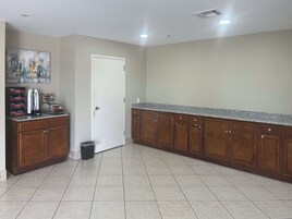 A kitchen with wooden cabinets, a granite countertop, and a trash can.