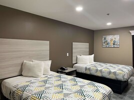 A hotel room with two beds, a nightstand, a phone, and a painting on the wall.