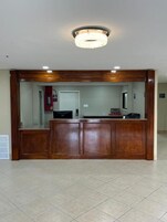 A reception area with a wooden reception desk, a chandelier, and a tiled floor.